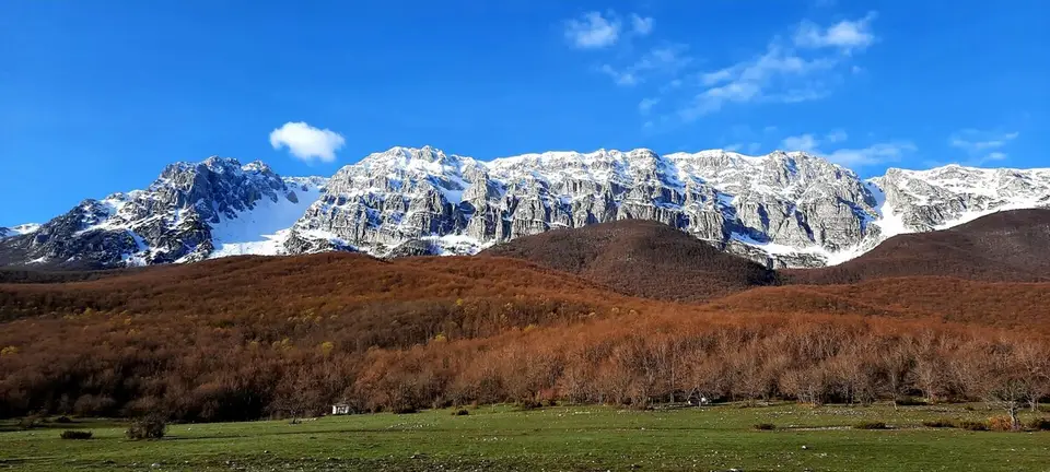 La catena innevata vista dal fondovalle, con i prati in primo piano.